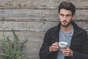 man with beard holding a cup of coffee