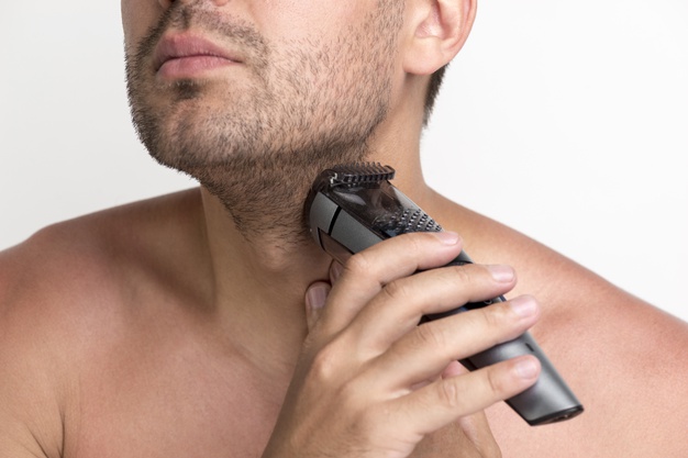 young man shaving beard with electric shaver